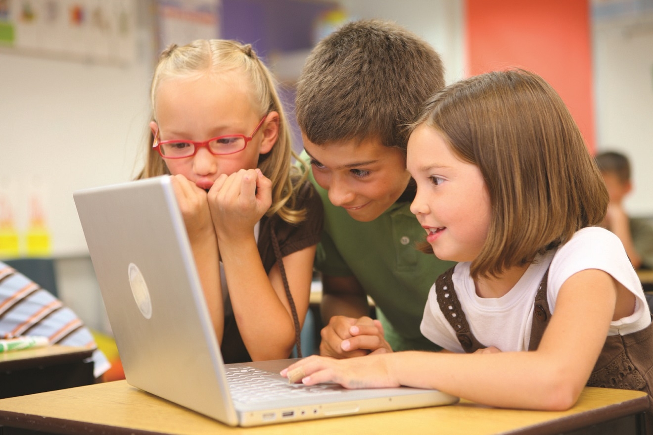 Kaks tüdrukut ja üks poiss istumas sülearvuti taga.